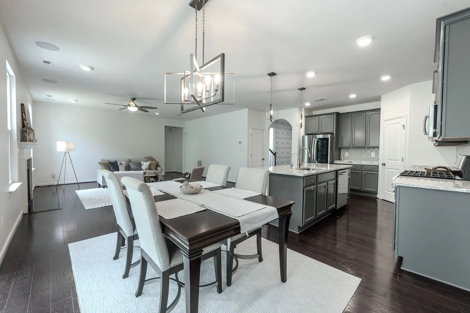 Staged dining room open to the kitchen with pendant chandelier and hardwood floors, greater Richmond VA