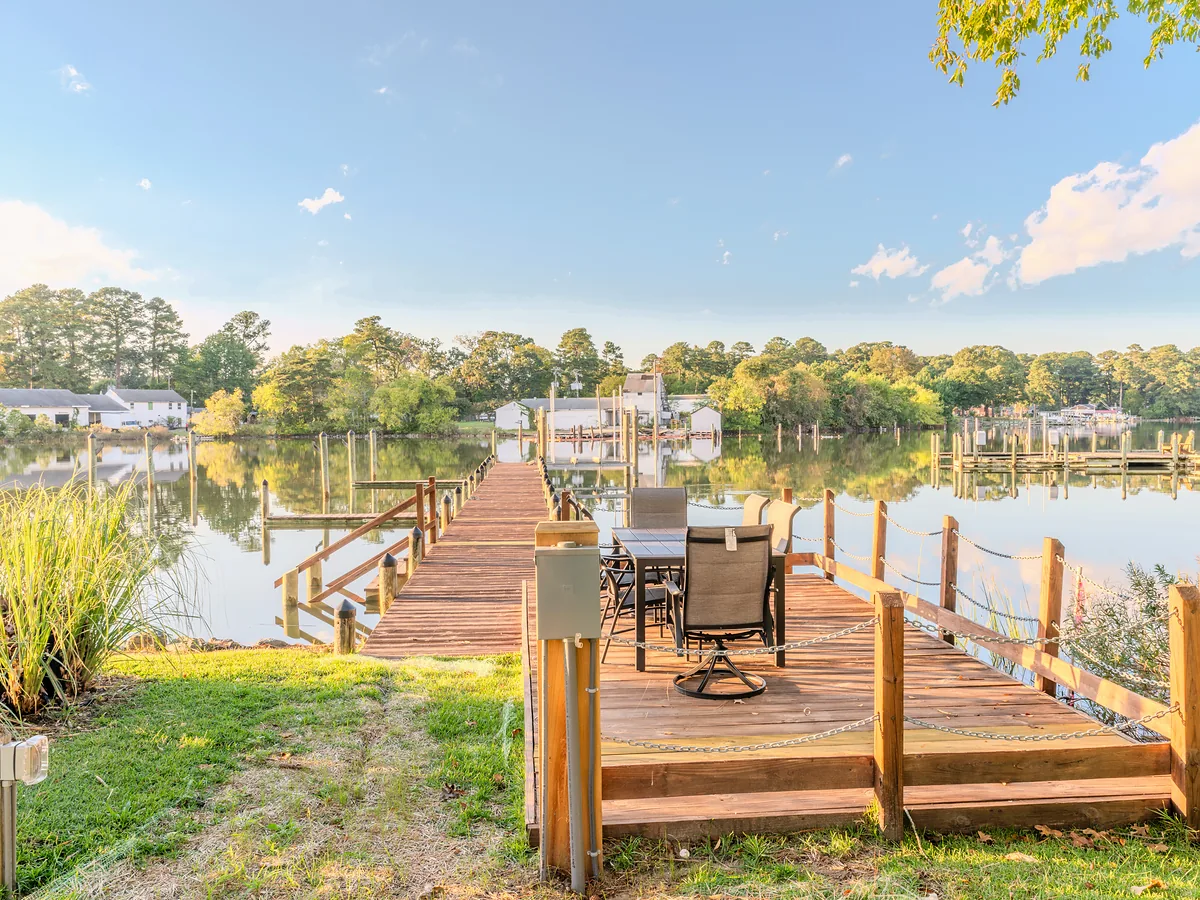 Private waterfront dock with patio seating over calm water at sunrise