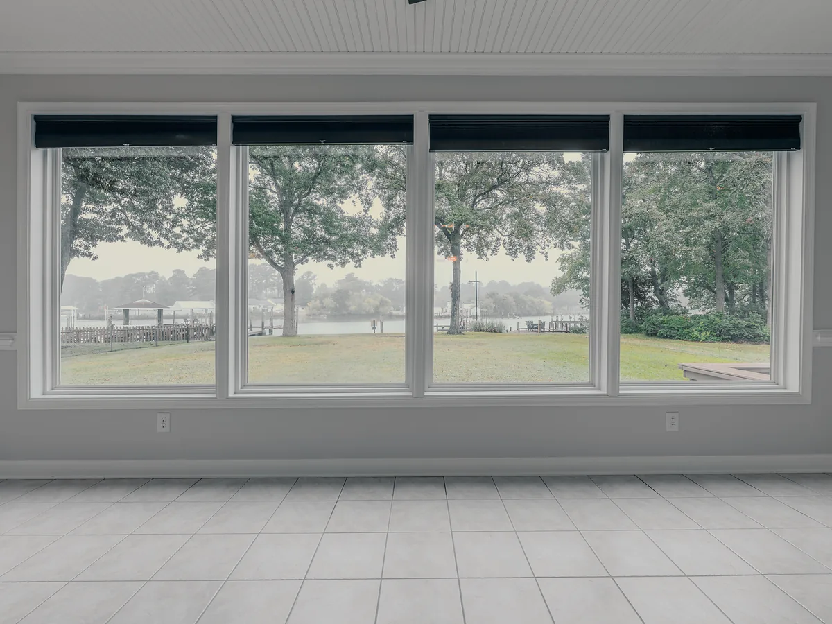 Sunroom with a wall of windows looking out over the lawn to the water